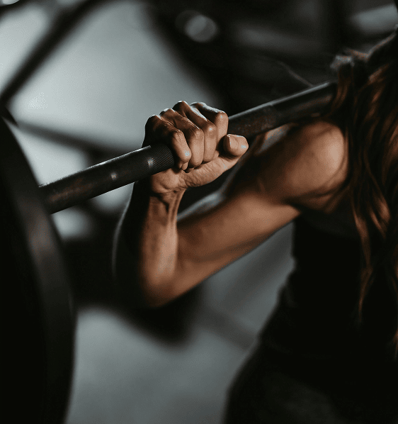 Femme en pleine séance de musculation, soulevant une barre chargée pour renforcer sa masse musculaire et sa puissance physique.